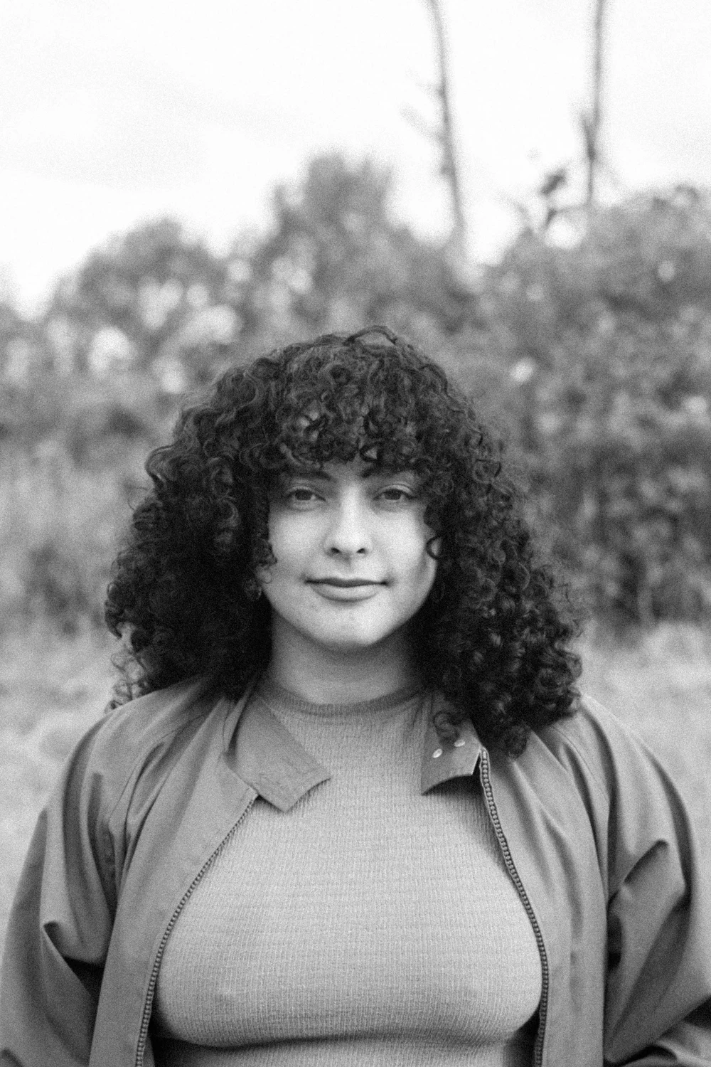 Black-and-white outdoor portrait of a Coocine member with curly hair