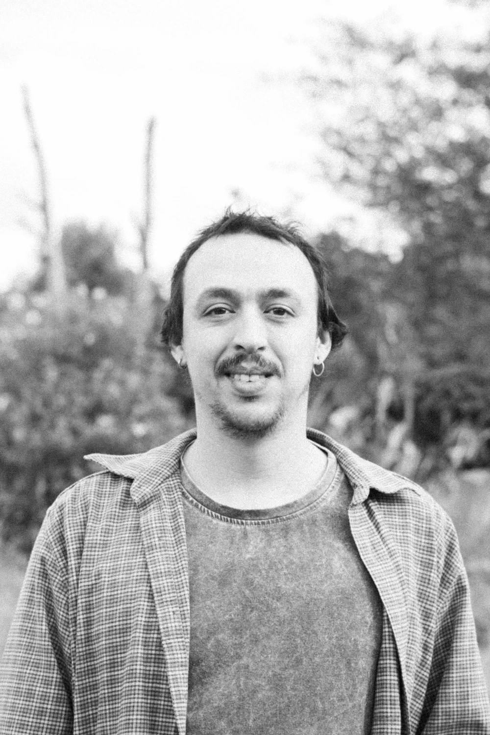 Black-and-white outdoor portrait of a Coocine member wearing a checked shirt