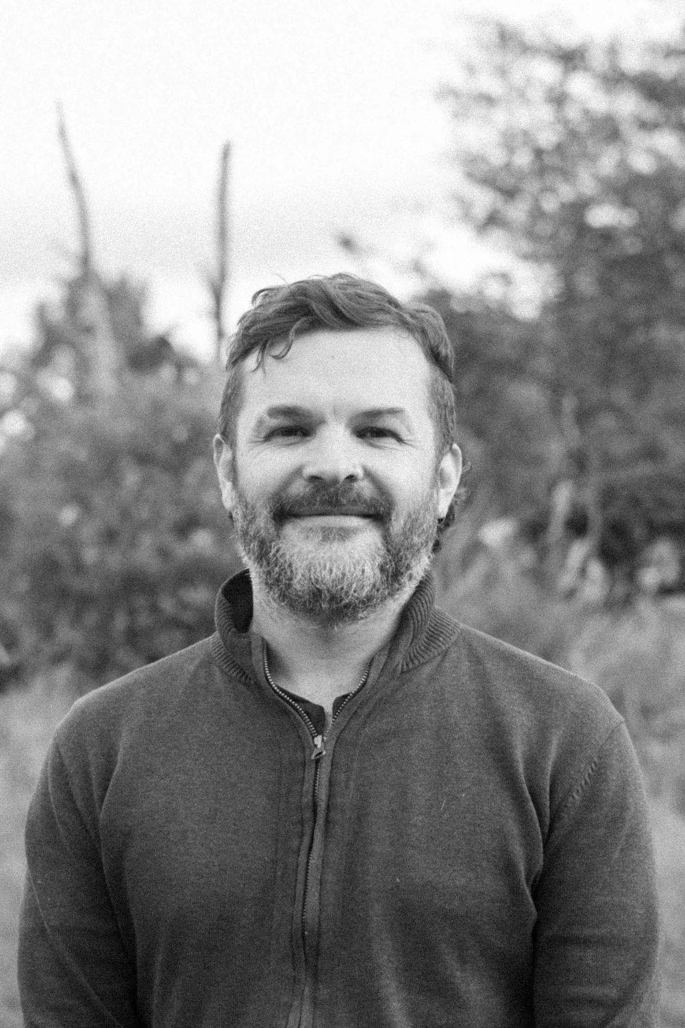 Black-and-white outdoor portrait of a Coocine member wearing a dark pullover
