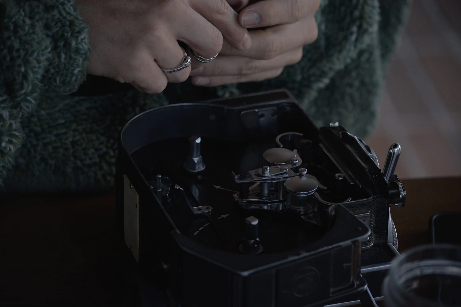 Manos trabajando con una cámara de cine de 16 mm abierta.