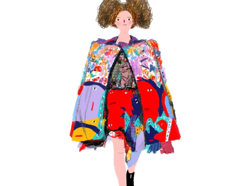 A model in a patchwork cape and a red skirt on the runway