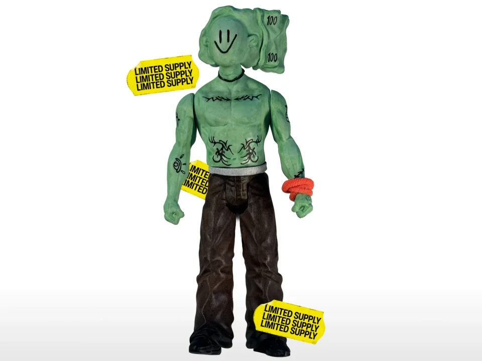 Uglyman, the UGLYCASH action figure: a green figure with a banknote for a head, in brown trousers, with yellow Limited Supply tags
