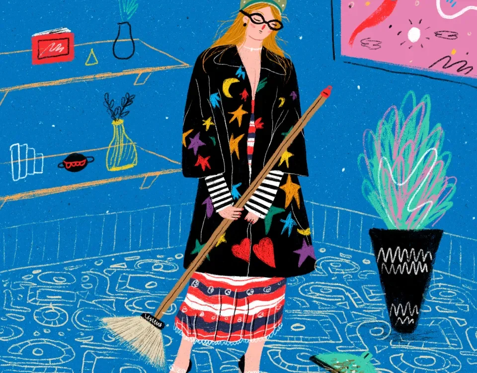 A woman in a patterned coat sweeping a blue tiled floor
