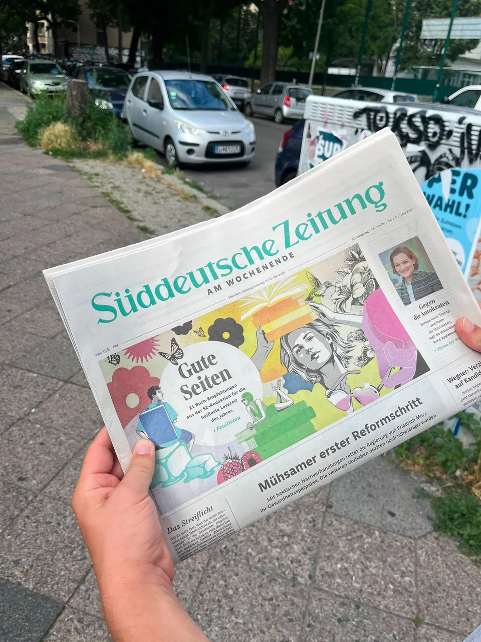 A hand holding a copy of Süddeutsche Zeitung, showing the newspaper cover